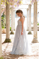 young bride in a wedding dress poses on the terrace