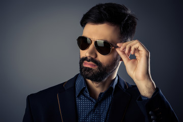 Attractive bearded man in suit touching his glasses