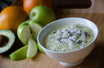 Green smoothie bowl with fresh fruit and chia seeds on bamboo tray