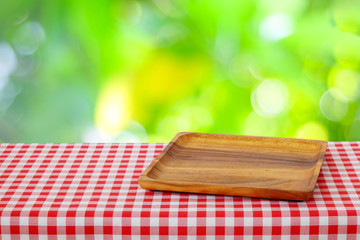 Empty wooden tray on red tablecloth over blur tree background