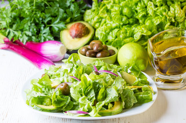 Green salad and ingredients lettuce, avocado, olives, oil, herb onion