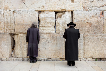 Fototapeta premium JERUSALEM, ISRAEL - MARCH 15, 2016: Two men praying at the men's section of the Wailing (Western) Wall in the old town Jerusalem (Israel)