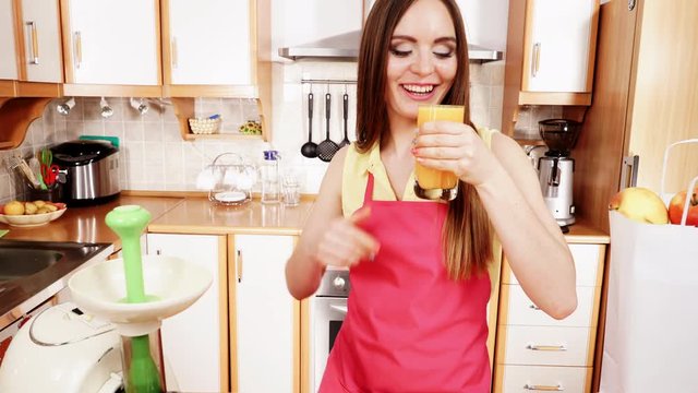 Woman in kitchen drinking fresh orange juice 4K