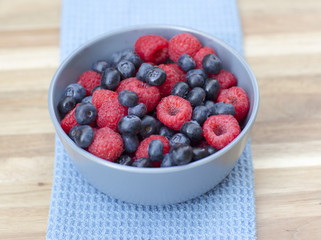 Dessert fresh berries in the bowl. Raspberries and blue-berries on a wooden table. Dessert, fresh berries close-up. 