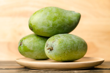 Raw mango on wooden plate
