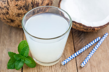 Coconut drink with pulp in glass on wooden table