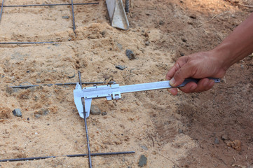 Workers using a verniercaliper measurement of rebar