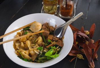 Thai style noodle,bowl of thai style pork noodle soup on wooden background and seasoning, Boat Noodle , Moo nam tok