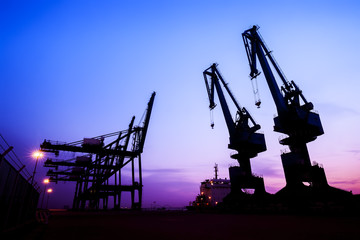 In the evening, the silhouette of port cranes