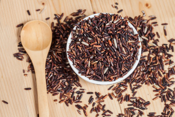Rice berry in bowl on wood background
