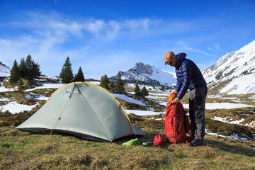 Fototapeta premium Hiker packing his backpack after camping in the mountains during springtime.