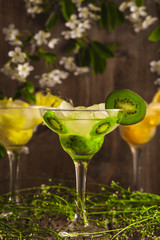 Three cocktails: pineapple, orange, kiwi. fruit soft drink with ice on a wooden background and flowers