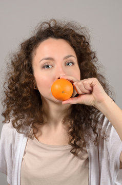 woman with tangerines near mouth