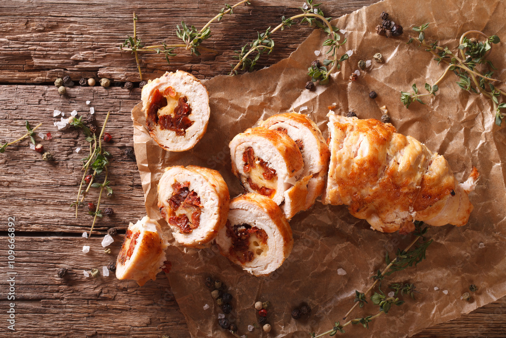 Wall mural chicken roll stuffed with cheese and sun-dried tomatoes close-up. horizontal top view