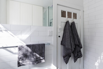 Luxury towels on door hooks in modern white bathroom