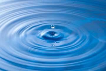 Naklejka na ściany i meble a water drop impact with water surface, causing rings on the sur