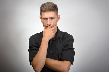 Portrait of the young thinking man with hand near face -  isolated on grey