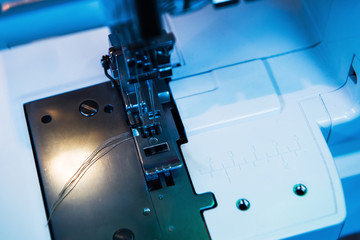 Electric sewing machine detail with its titan needle and thread in blue technological background