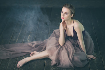 Obraz premium Young woman sitting barefoot on the floor in smoke thinking