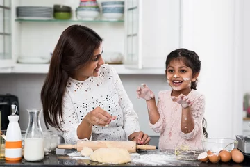 Foto auf Acrylglas Kochen Verspieltes kleines Mädchen, das mit ihrer Mutter kocht