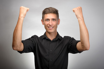 Fototapeta premium Happy businessman celebrating his success over gray background. Looking at camera
