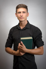 handsome young man standing and looking. male holding book in hands