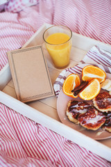 breakfast in bed, pancakes with fruit and juice and notebook on a tray