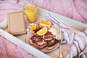 breakfast in bed, pancakes with fruit and juice and notebook on a tray