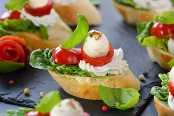 Käsehäppchen mit Tomate und Mozzarella, mit Basilikum und Frischkäse auf Baguette mit...
