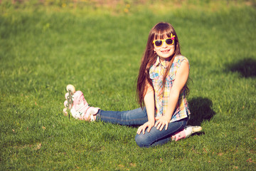 girl wearing roller skates sitting on grass in the park.