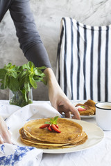 Female hands holding plate with crepes, selective focus