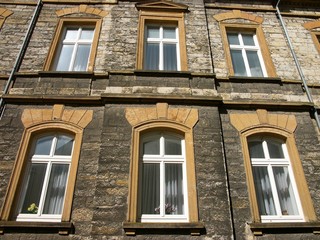 Sanierte Fassade aus Bruchstein mit Ornamenten aus Sandstein in Beige und Naturfarben vor blauem...