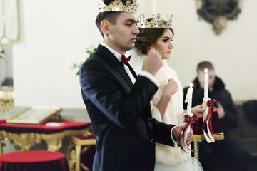 Bride and bridegroom standing in crowns during the ceremony in t