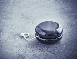 Black wooden yoyo on stone table. Close up of vintage toy. Concept of nostalgia, childhood and old-fashioned entertainment.
