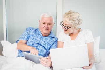Senior man pointing at tablet with wife