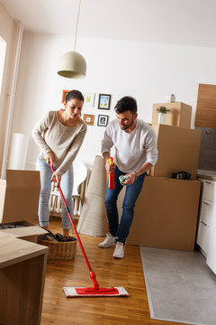Young married couple cleaning and selecting furniture and accessories in their new home. Moving house.	