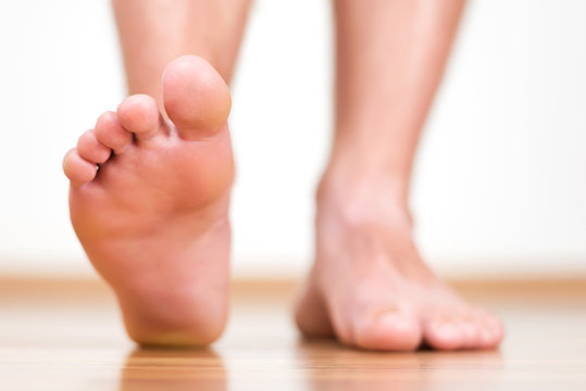 Healthy male feet stepping over home-like background