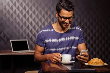 Man using his smartphone and drinking coffee