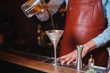 bartender pouring a cocktail into glass, close-up.