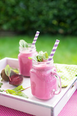Beet smoothie in a jar with a straw and ingredients on the background. Vertical shoot.