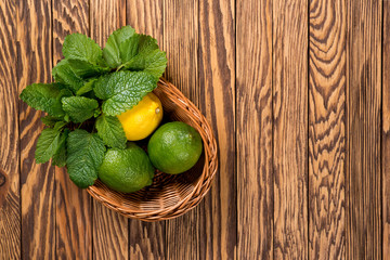 Yellow lemon, lime and green mint leaves on a wooden background. Top wiev