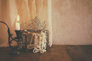 diamond queen crown, white pearls next to burning candle