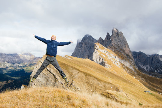 Man tourist jumping with happiness on a background of mountains. Dolomite, Alps