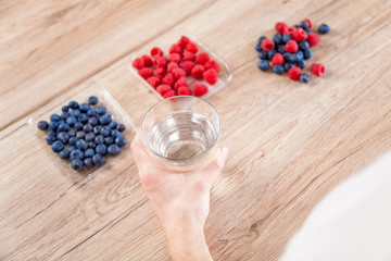 Closeup on man with a glass of water healthy berries on table