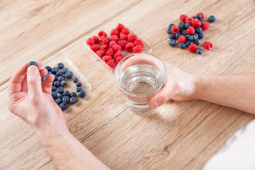 Closeup on man with a glass of water healthy berries on table