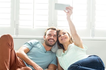 Couple taking selfie while relaxing on bed