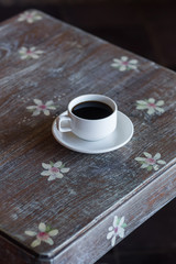 Black coffee on vintage wooden table with flowers ornament