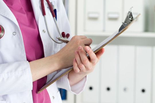 Close up view of female doctor hands holding clipping pad