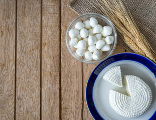 Tzfat cheese, wheat, cottage cheese, and mozzarella balls on wooden deck for Shavuot celebration. 