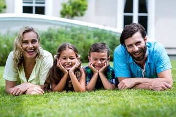 Portrait of happy family lying on grass at yard 